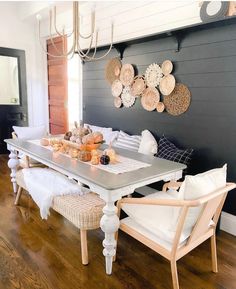 a dining room table with white chairs and plates on the wall