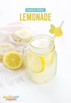 a glass jar filled with lemonade next to cookies