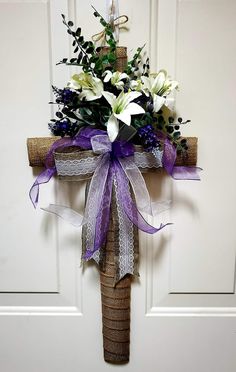 a cross decorated with flowers and purple ribbon hangs on the front door's wall