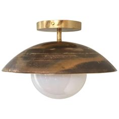 an antique brass ceiling light with a white glass ball hanging from it's side