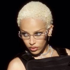 a close up of a person wearing glasses with blonde hair and piercings on her ears