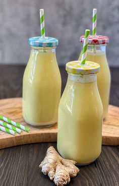 two glass jars filled with yellow liquid next to a green and white striped straw