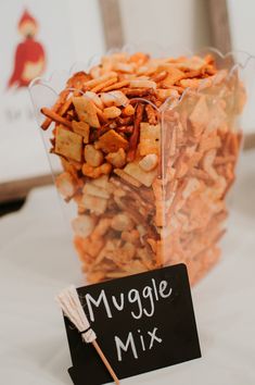 a cup filled with lots of food next to a sign that says muggle mix