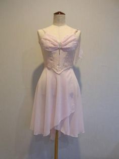 a white dress on a mannequin stand against a wall