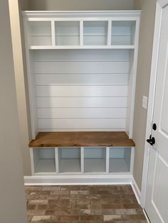 an empty room with white shelves and wood flooring on the wall, next to a door