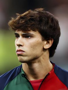 a close up of a young man wearing a red, green and blue shirt looking off to the side