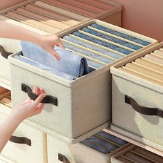 a woman is reaching for some clothes in a drawer with two bins on it