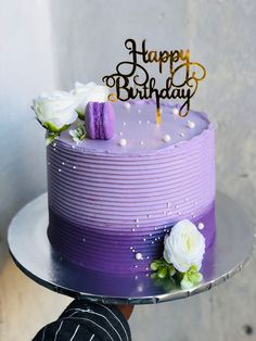 a birthday cake with purple frosting and white flowers