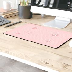 a computer desk with a pink mouse pad and keyboard on it, along with other office supplies