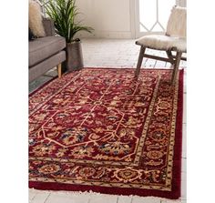 a red area rug with an ornate design on the bottom, and a chair next to it