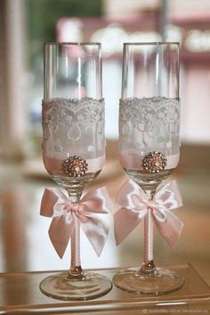 two wine glasses with pink bows and laces on them are sitting side by side