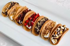 five tacos lined up on a white plate with the words, s'more tacos