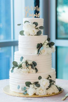 a wedding cake with white flowers and greenery on the top is being viewed on instagram