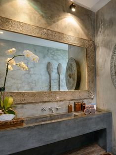 a bathroom with a large mirror above the sink and two vases on the counter