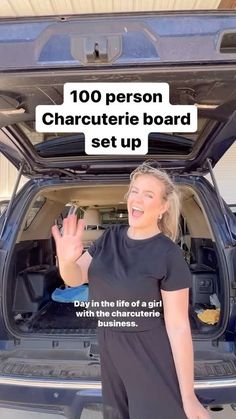 a woman is standing in front of the back of a car with her hand up