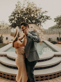 a man and woman dancing in front of a fountain