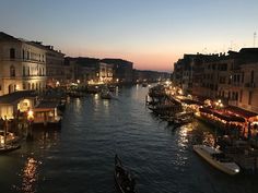 boats are parked along the side of a river at night in an urban area with buildings and lights on both sides