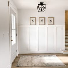 an empty room with stairs and pictures on the wall above it's carpeted floor