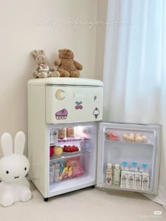 an open refrigerator sitting next to a stuffed animal