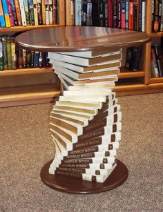 a wooden table topped with books in front of a book shelf filled with books on top of carpeted flooring