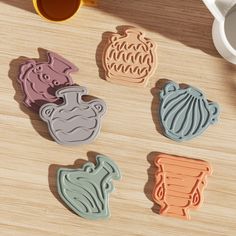 four cookie cutters sitting on top of a wooden table next to a cup and saucer