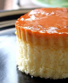 a piece of cheesecake with caramel sauce on top sitting on a black plate