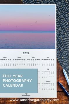 a calendar sitting on top of a wooden table next to a pen and paper with the words full year photography calendar