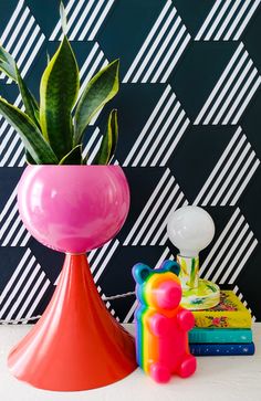 a pink vase sitting on top of a table next to a stack of books and a toy bear