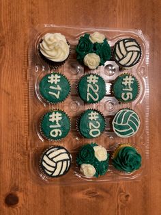 cupcakes decorated with green and white icing in a plastic container on a wooden table