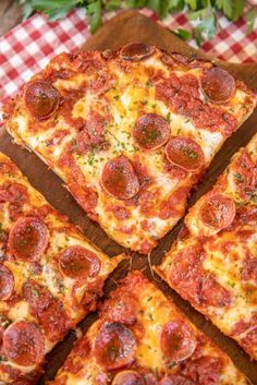 four slices of pepperoni pizza sitting on top of a wooden cutting board with red and white checkered tablecloth