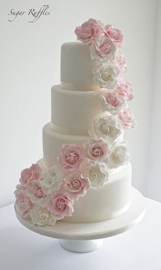 a three tiered wedding cake with pink and white flowers