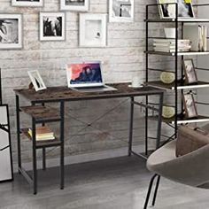 a desk with a laptop on it in front of a brick wall and several pictures