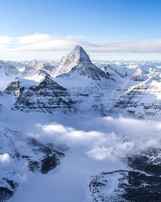 the mountains are covered in snow and clouds as seen from an airplane window, looking down on them