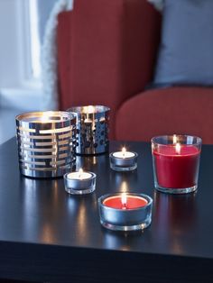 three candles sitting on top of a table next to a red chair in a living room