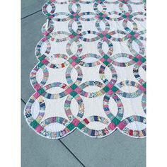 a quilted table runner with circles on the top and bottom, sitting on concrete