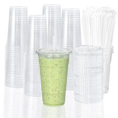 there are many plastic cups with straws next to each other on the white table