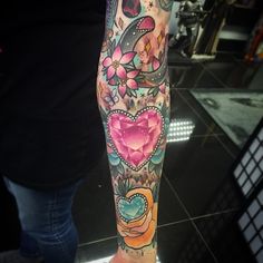 a woman's leg with colorful tattoos and flowers on her left arm, which is decorated with hearts