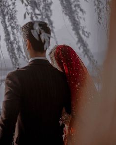 a man and woman standing next to each other in front of some snow covered trees