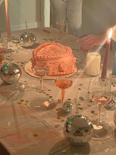 a man standing next to a table with a cake on it and candles in front of him