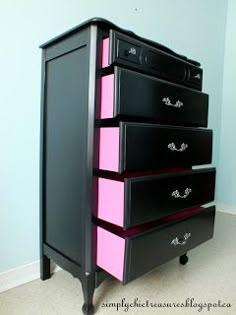 a black dresser with pink drawers in a room