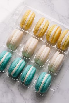 there are many different colored macaroons in the tray on the table, one is blue and one is yellow