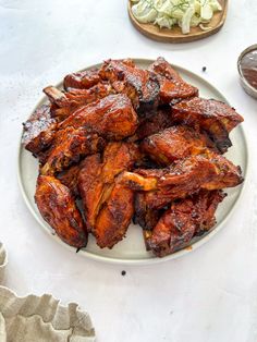 a white plate topped with chicken wings next to a bowl of coleslaw