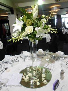 a vase with white flowers on a table in a room filled with tables and chairs