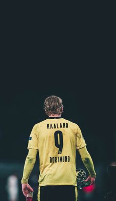 the back of a soccer player's yellow jersey with his hands on his hips