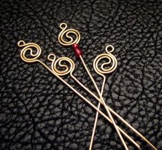 three knitting needles sitting next to each other on a black surface with swirly designs