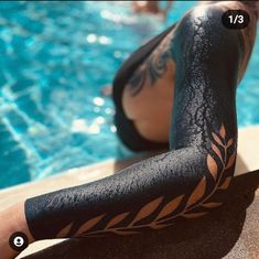 a person with tattoos on their legs next to a swimming pool