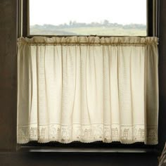 an open window with white curtains and a plaid umbrella