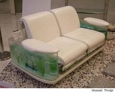 a white leather couch sitting on top of a marble floor next to a glass vase