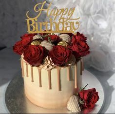 a birthday cake decorated with red roses and gold letters