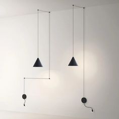 three black lamps hanging from the ceiling in a room with white walls and flooring